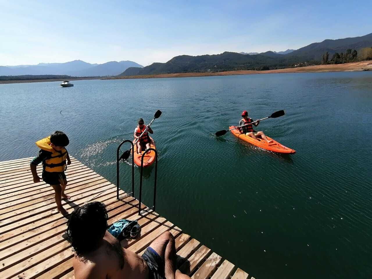 A wooden dock extending into a calm lake with mountains in the background.