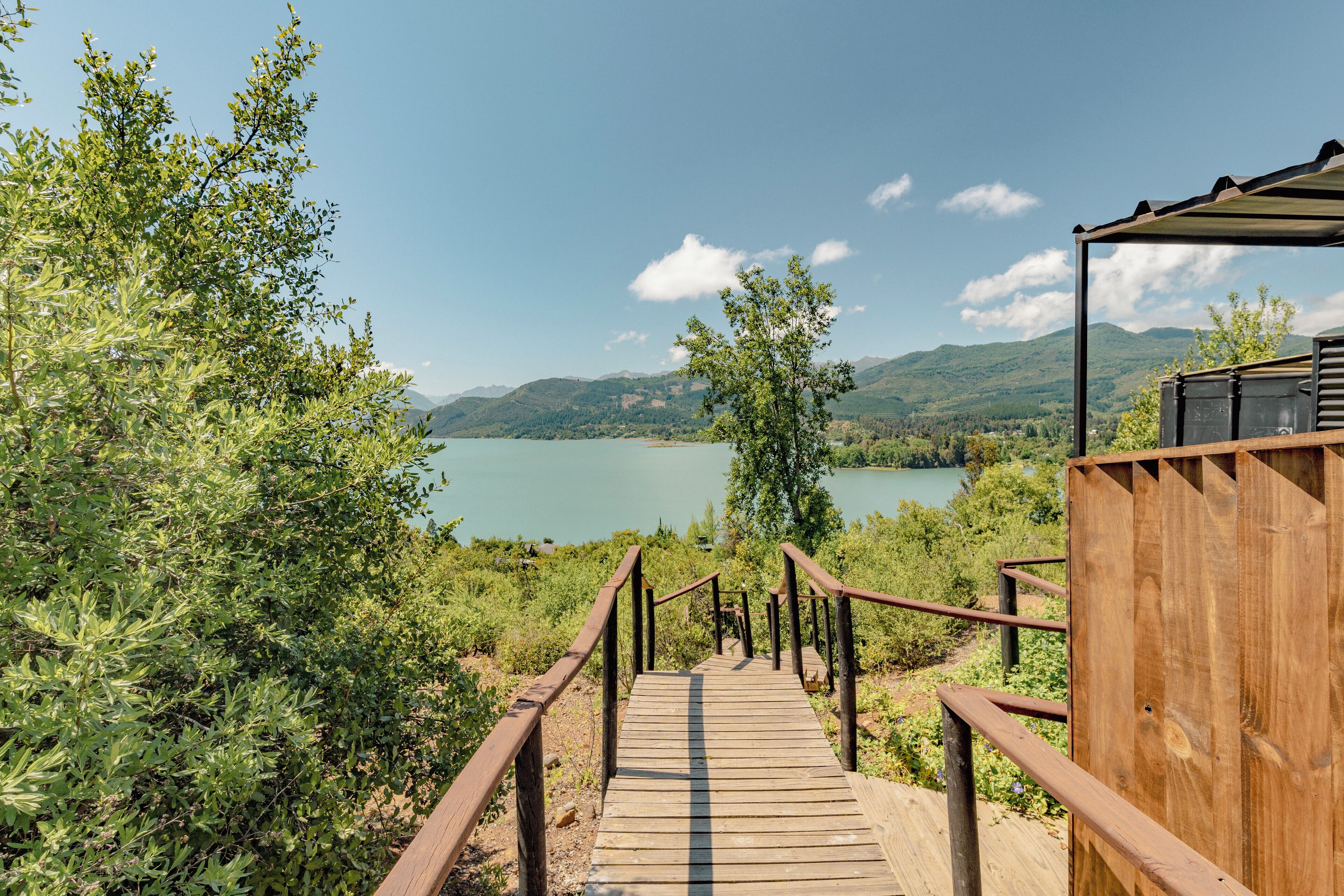 A wooden staircase leading to a wooden structure with a view of a lake and mountains.