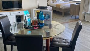 A hotel room with a dining area, a bed, a television, and a window with curtains. - Lovely 1-bedroom w/ocean view, WiFi, AC & FREE Parking (Honolulu)