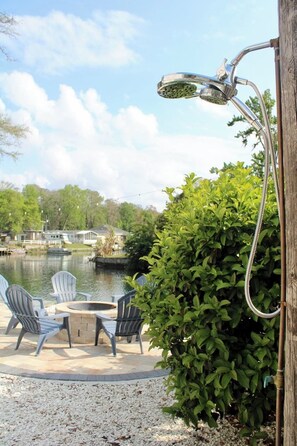 Une terrasse avec des fauteuils Adirondack, un foyer et une vue sur un lac.