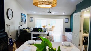 A dining area with a table set for four, a ceiling fan, and a view into the living room. - Entire Home Direct River Access Momma Marie’s (Spring Hill)