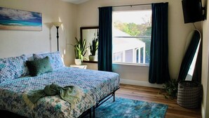 A bedroom with a bed, a window with curtains, a TV, a lamp, and a plant. - Entire Home Direct River Access Momma Marie’s (Spring Hill)
