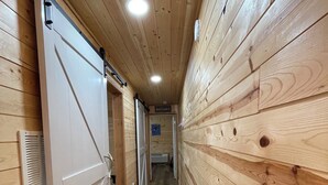 A narrow hallway with wooden walls and a white door on the left.