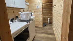 A compact laundry room with a washing machine, dryer, and a drying rack.