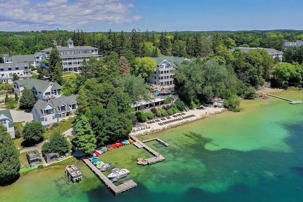 Scenic lake shoreline surrounded by greenery & lakeside homes.