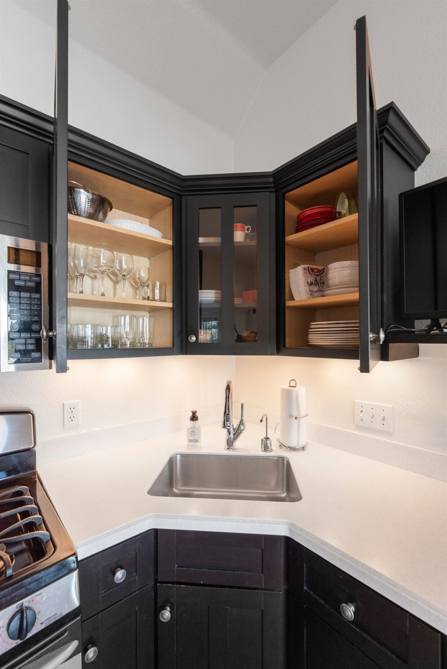A modern kitchen with black cabinets, a stainless steel sink, and a built-in oven.