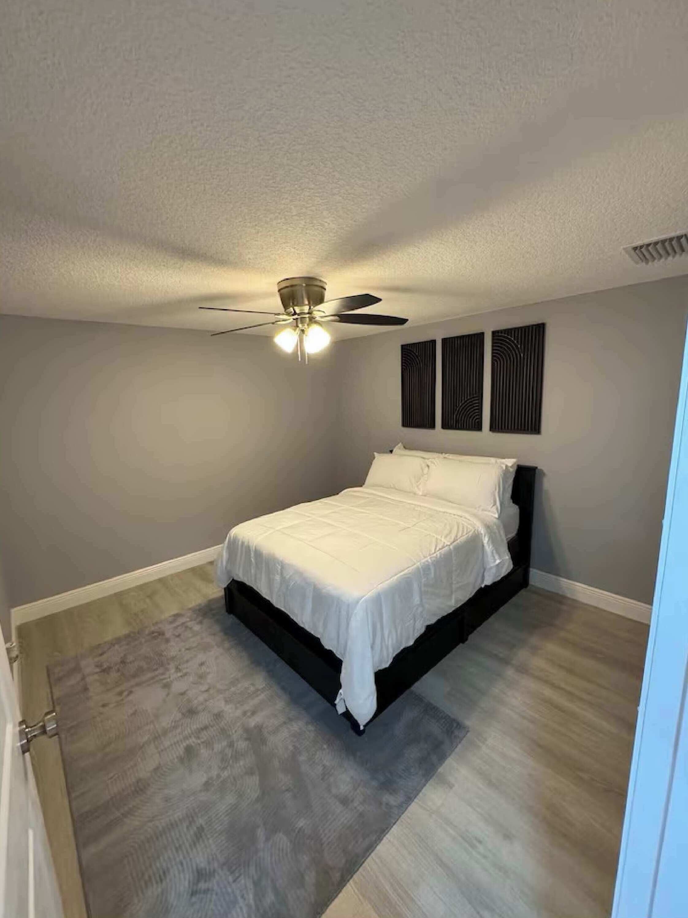 Une chambre à coucher avec un lit, un ventilateur de plafond et un luminaire.