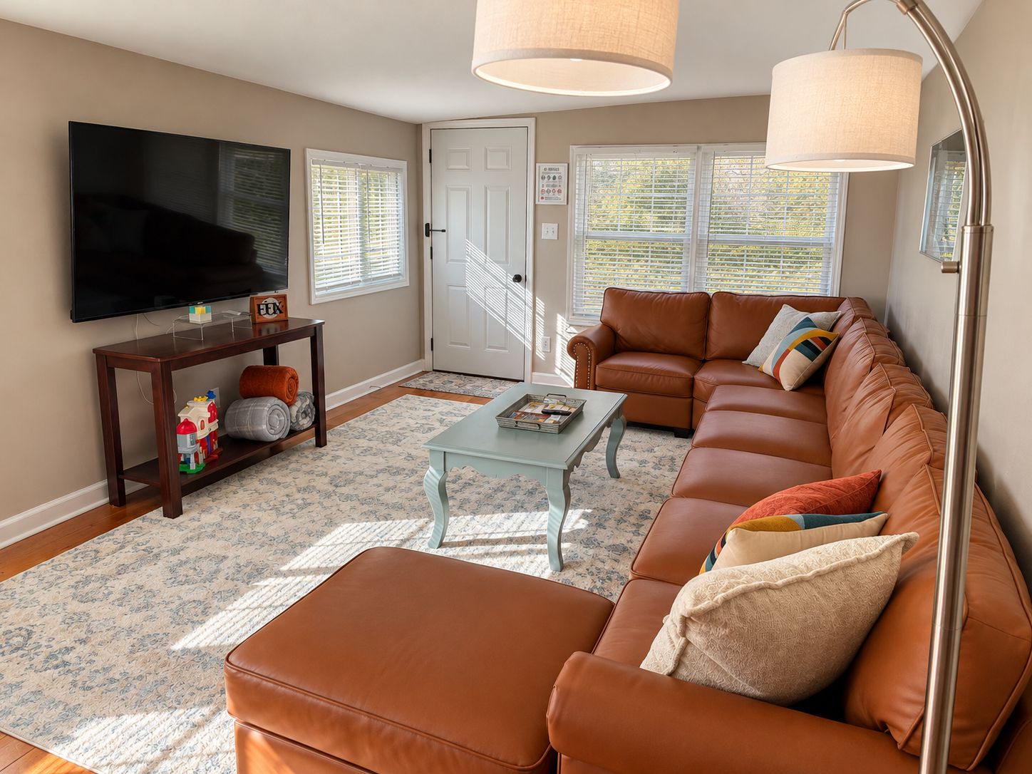 A living room with a television, sofa, coffee table, and a door with a staircase.