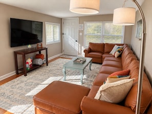 A living room with a television, sofa, coffee table, and a door with a staircase.