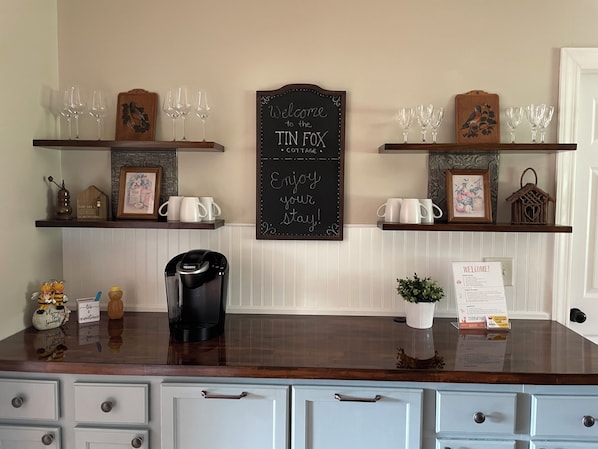 Un comptoir de cuisine avec une machine à café, des tasses et un panneau d’affichage en ardoise.