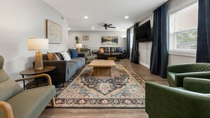 A modern living room with a sofa, armchairs, a coffee table, and a patterned rug. - A&M Getaway • Game Room • Mini Golf • Sleeps 12 (Bryan)