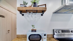 Une cuisine équipée d’un four à micro-ondes, d’un four traditionnel, d’une armoire en bois et d’une étagère ornée d’une plante et d’une pancarte.