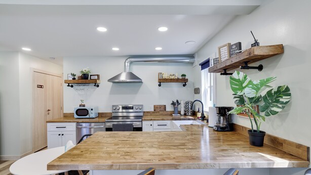 Une cuisine moderne avec un îlot central en bois, des appareils électroménagers en acier inoxydable et une plante en pot.