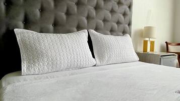 A neatly made bed with a tufted headboard, white bedding, and two pillows.