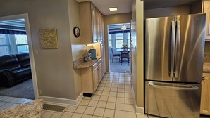 A modern kitchen with a stainless steel refrigerator, wooden cabinets, and a dining area with a table and chairs. - Large 3 Bedroom, 2 Bath Home, Premium Kitchen, Large Family & Living Rooms (Dayton)