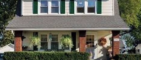 A two-story house with a front porch, a chimney, and a well-maintained lawn.