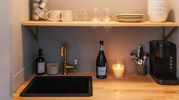 A kitchen with a wooden countertop, a sink, a coffee maker, a wine bottle, and a candle.