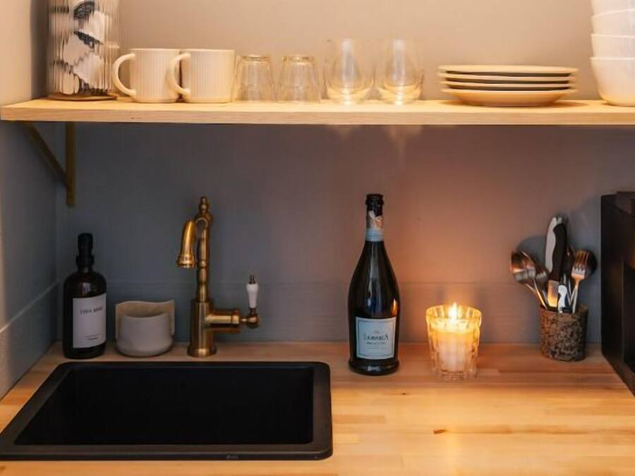 A kitchen with a wooden countertop, a sink, a coffee maker, a wine bottle, and a candle.