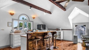 A spacious kitchen with a wooden bar area, white cabinetry, and a large window offering a view of the outdoors. - The Ipswich Inn (Ipswich)