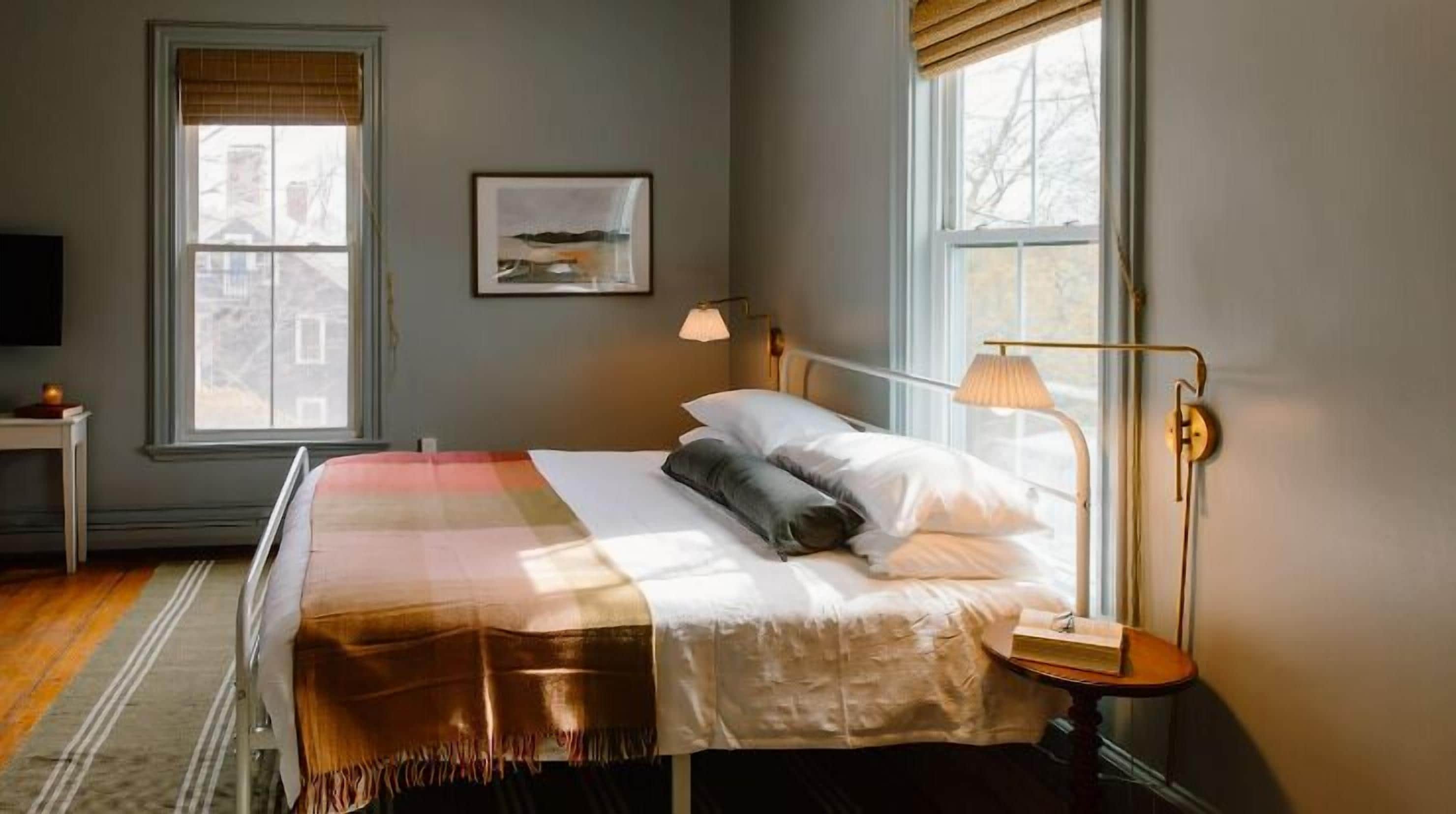 A bedroom with a bed, bedside table, lamp, and a framed picture on the wall.
