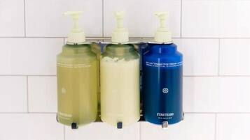 Three bottles of liquid soap on a tiled wall.