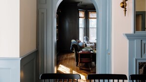 A hallway with a wooden floor, a blue door, and a black chair in the foreground. - The Ipswich Inn (Ipswich)