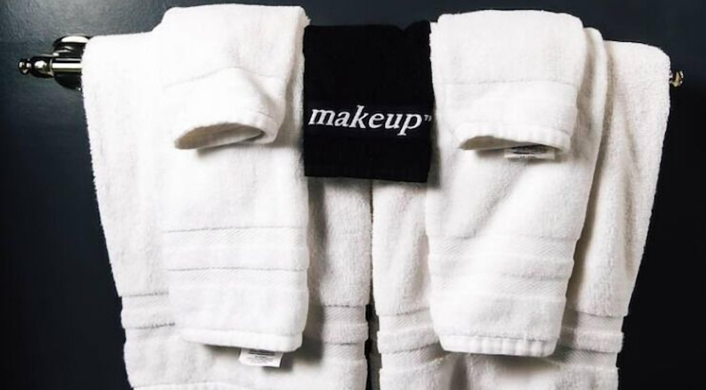 Een witte handdoek met de tekst 'makeup' erop, hangend aan een rek.