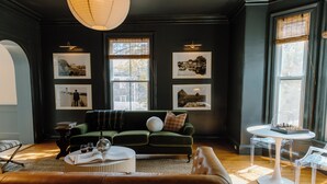 A modern living room with a green sofa, a leather couch, and a round coffee table. There are framed pictures on the wall and a chessboard on a small table. - The Ipswich Inn (Ipswich)