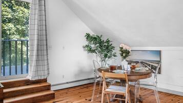 A dining area with a wooden table, chairs, and a view of a scenic landscape through a window.