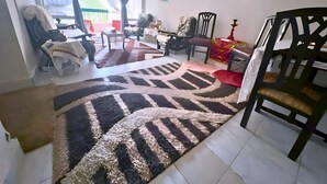 A living room with a large rug, a dining table, chairs, and a sofa. - Private Rooms in Shared Apartment, Prime Location, Port Said Downtown (Al Zehour)