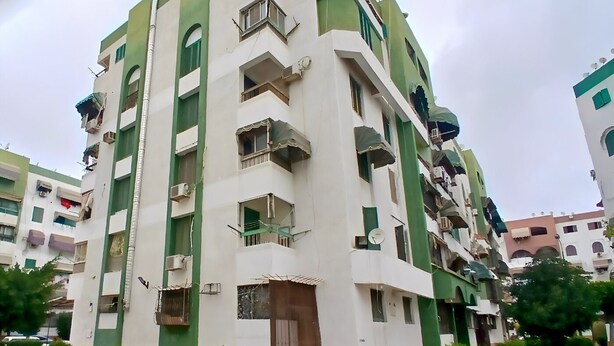 A multi-story residential building with balconies, air conditioning units, and a gated entrance. - Private Rooms in Shared Apartment, Prime Location, Port Said Downtown (Al Zehour)