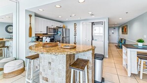 A modern kitchen with a central island, white cabinets, and a decorative word 'DESTINY' on the wall. - Destin Dreams 🌊 Gulf-View Condo at Sterling Shores Resort in Destin, Florida (Destin)
