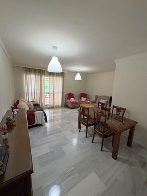 A spacious living area with a sofa set, a dining table with chairs, and two pendant lights. - Los Nidos Apartment, Carihuela (Torremolinos)