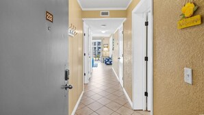 A hotel hallway with a number 232 door, a blue sofa, and a lamp in the distance.