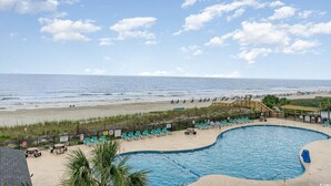 A pool area with a view of the beach and ocean.
