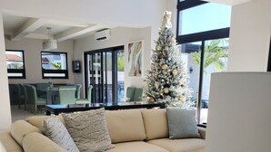 Een moderne woonkamer met een beige hoekbank, een marmeren salontafel en een kerstboom.