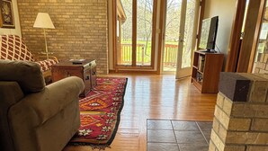 A cozy living room with a sofa, a rug, a fireplace, and a television.