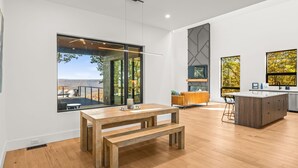 A modern kitchen with a large island, wooden flooring, and large windows offering views of the outdoors. - Secluded, modern, spectacular views, hot tub on 18 acres. Firepit,games & more! (Sewanee)