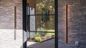 A modern building entrance with a glass door, brick walls, and a small garden area visible through the door. - Secluded, modern, spectacular views, hot tub on 18 acres. Firepit,games & more! (Sewanee)