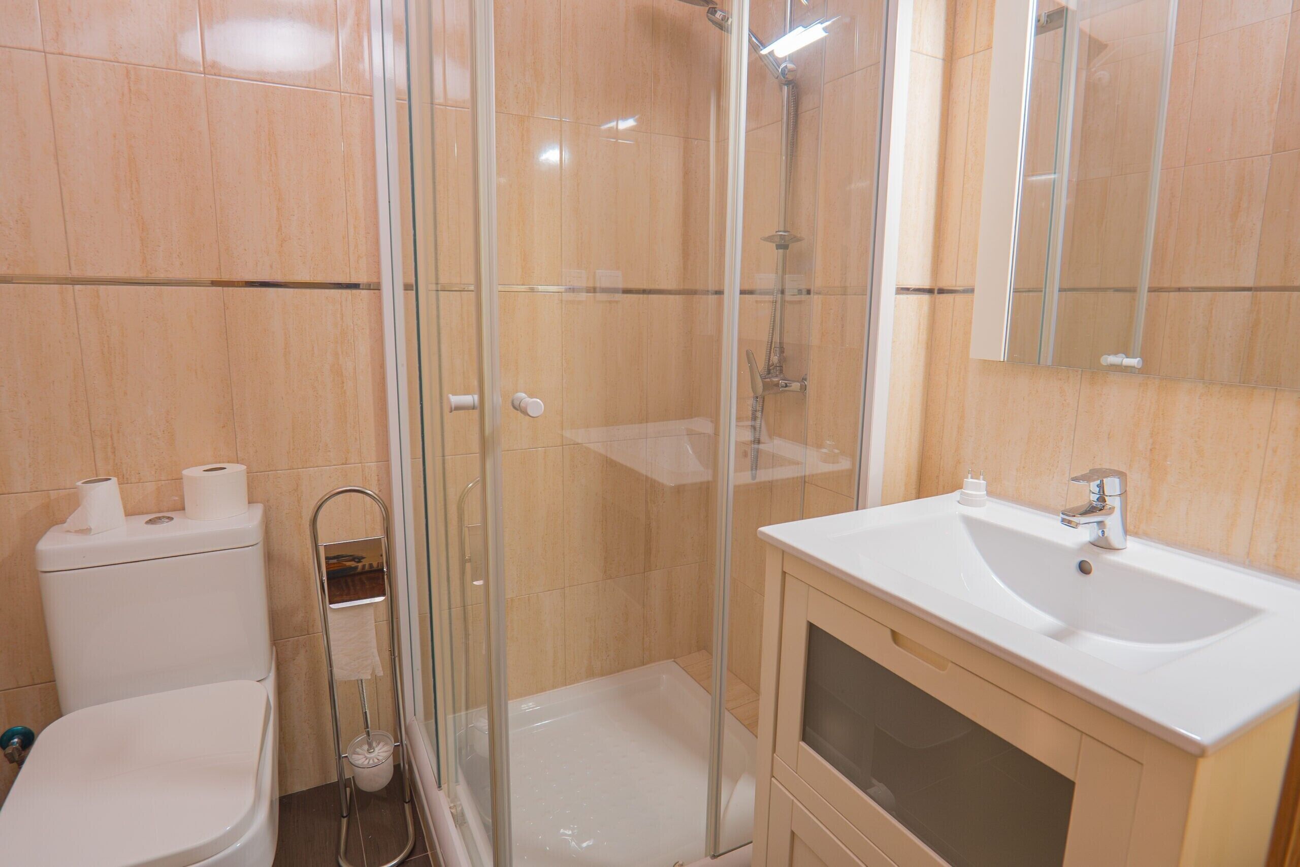 Une salle de bain avec une douche à parois de verre, un lavabo blanc et des toilettes.