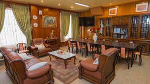 Una habitación tradicional con un conjunto de sofás, una mesa de comedor, sillas, un televisor y una estantería.