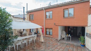 Un edificio residencial con un patio empedrado, mobiliario exterior y una antena parabólica.