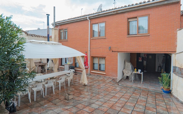 Un edificio residencial con un patio empedrado, mobiliario exterior y una antena parabólica.