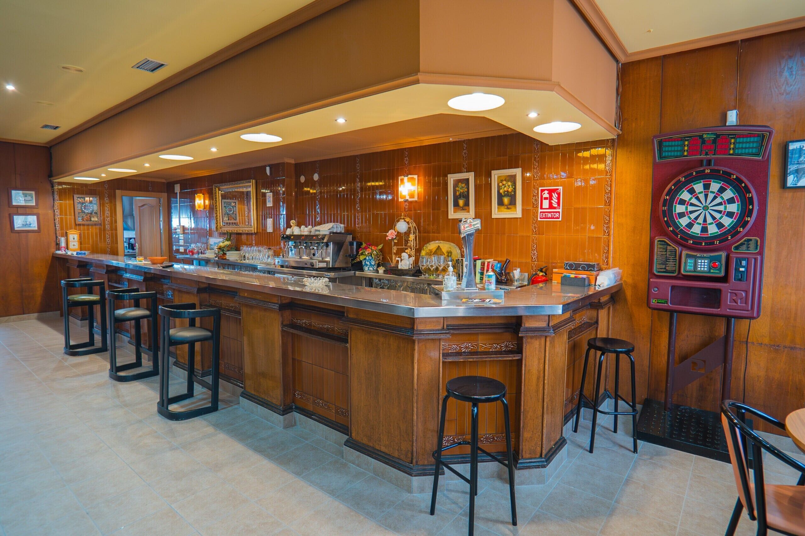 A bar area with a dartboard, bar stools, and a counter with a cash register.
