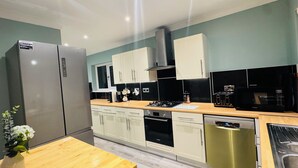 A modern kitchen with stainless steel appliances, white cabinets, and a wooden countertop. - Spacious 4BR house close to Gatwick Airport. (Crawley)