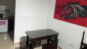 Ein Essbereich mit Tisch und Stühlen, im Hintergrund eine Küche und ein rotes abstraktes Gemälde an der Wand.