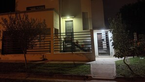 Ein modernes, zweistöckiges Haus mit Balkon, kleinem Vorgarten und gut beleuchtetem Eingang.