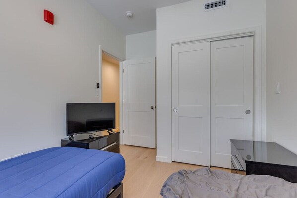 A bedroom with a bed, a TV, a desk, and a wardrobe.