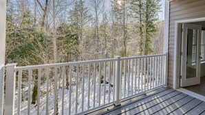 A wooden deck with a white railing overlooking a snowy forest.