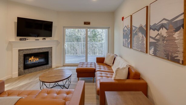A modern living room with a fireplace, a television, a sofa, and a dining table.